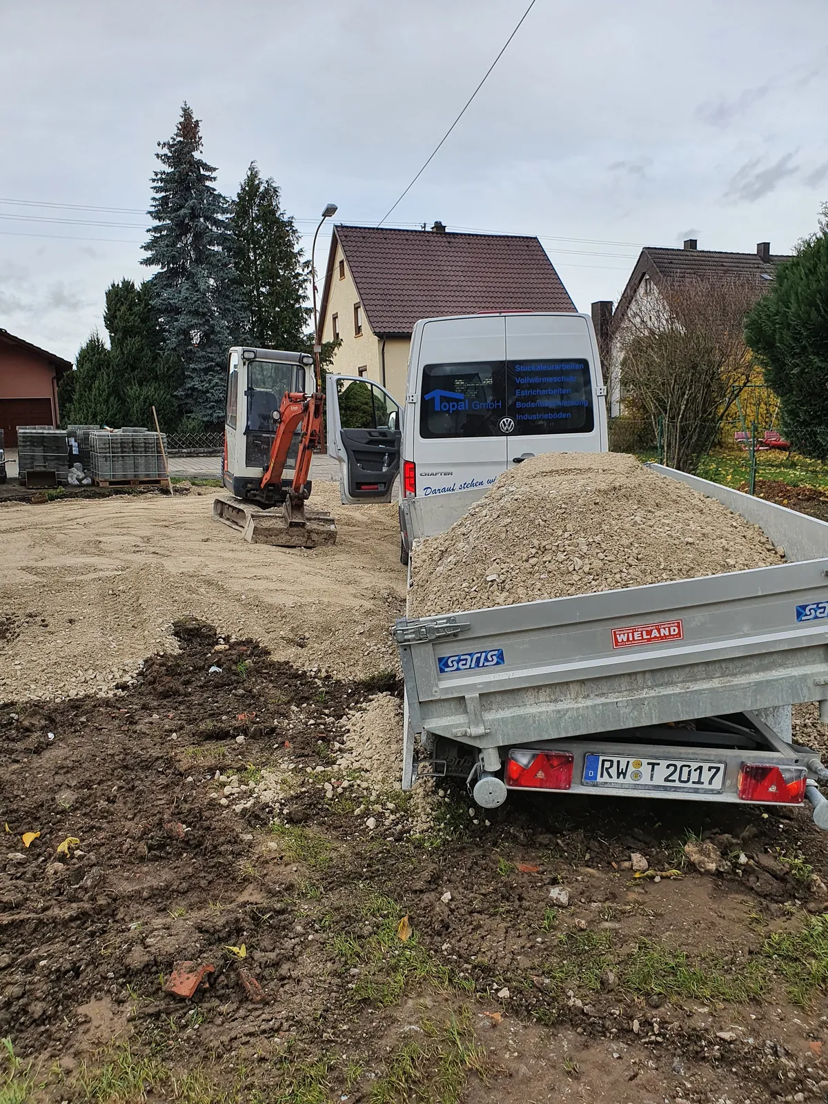 Minibagger und Anhänger der Topal GmbH bei Erdarbeiten in einem Wohngebiet